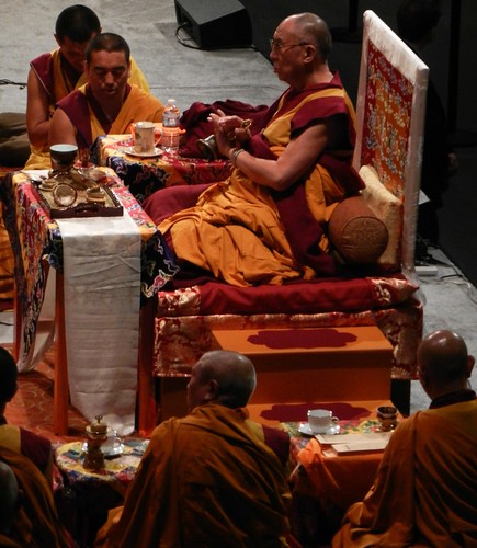 His Holiness the 14th Dalai Lama praying with his hands crossed with a dorje and bell, on his short throne, with lamas, tea, ritual impliments, silks, orange robe, steps, tables, Kalachakra for World Peace, Washington D.C., USA by Wonderlane