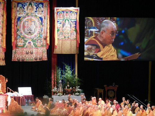 Buddhist nuns assembled on one side of the stage over which His Holiness the 14th Dalai Lama's video appears, shrine, Kalachakra mandala and White Arya Tara brocade thangkas, Kalachakra for World Peace, Washington D.C., USA by Wonderlane