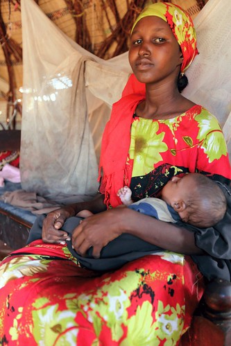 Nouria, sits in her home, with her child Abdi, two, on her lap. She lives in the village of Abdiaziz, just outside Wajir, Kenya. by Save the Children Australia