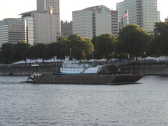 A tiny tugboat shoves a barge past the steamtug Portland