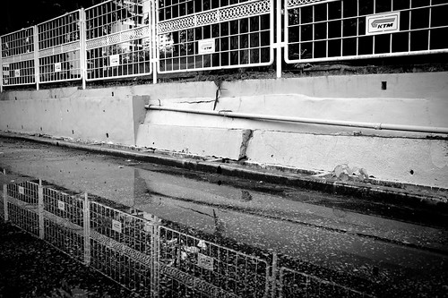 Reflection of the KTM station fence in a puddle of water
