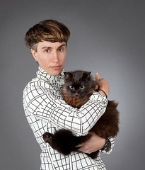 Tender Forever, a white woman with short brown hair, holds a cat and looks at the camera