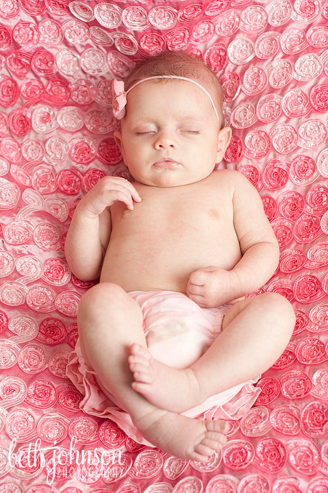 baby girl at two months on pink blanket with rosettes