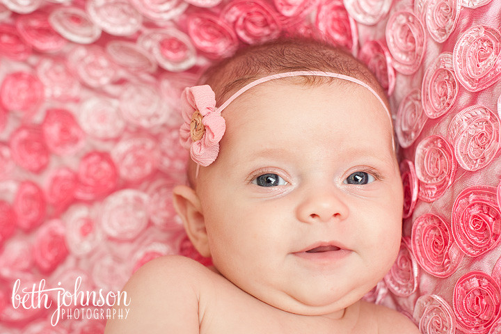 two month old baby girl with big blue eyes on pink blanket
