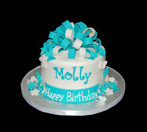 turquoise and whit birthday cake with butterflies and flowers topped with a bow