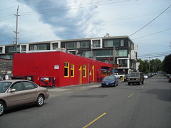 A vividly red building with a modern condo behind it