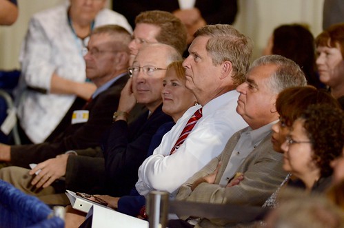 Agriculture Secretary Tom Vilsack (center white shirt) listens to President Barack Obama speaking at the Northeast Iowa Community College for a White House Rural Economic Forum on August 16, 2011. Agriculture Secretary and chair of the White House Rural Council, Tom Vilsack, notes that the President’s visit will focus on agriculture’s contribution to the national economy, and how to create more jobs in rural America. USDA Photo by Lance Cheung. 