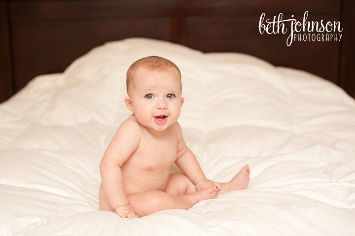 baby girl on bed with white comforter six months