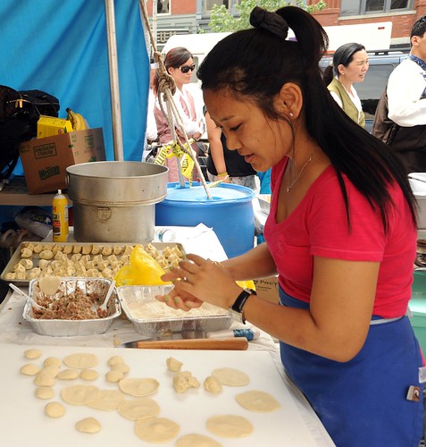 Tibetan woman making mo-mos pastry - dough and filling, wearing her hair back in a ponytail,  for cooking at the white tent market, Kalachakra for World Peace, near Verizon Center, Washington D.C., USA by Wonderlane