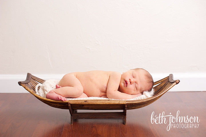 newborn baby boy in wooden platter boat
