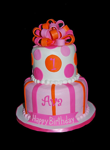 pink and orange 2 tier first birthday cake topped with a bow