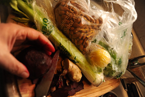 Cutting a beet stains fingers red; making a salad on a cutting board in the sink, shelled almonds, celery, celantro, lemon, veggies in plastic bags, Broadview, Seattle, Washington, USA by Wonderlane