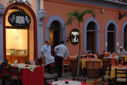 Two business men chatting, Pia Gioielli jewelers lion sign, a waiter from Pedro & Lola restaurant, set tables, palm tree, customers, Machado Square, Centro Historico, Sinaloa, Mexico
