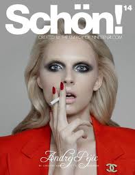 andrej pejic on the cover of schon magazine smoking a cigarette and wearing a red blazer with a chanel brooch