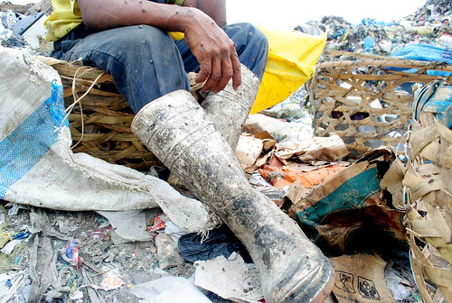Flies rest on the arm and legs of a scavenger who is resting at the Inayawan landfill.