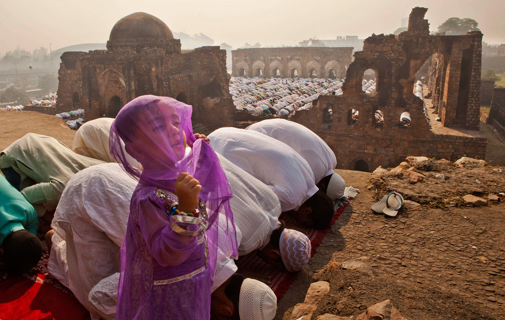 A young Indian Muslim girl gestures as others offer prayers during Eid al-Adha in New Delhi