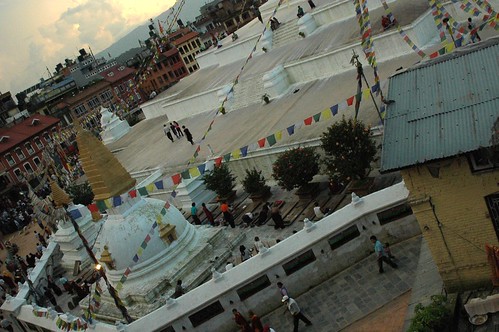 Tibetan Buddhists doing prostrations on the eastern side of Boudha stupa, twilight, clouds, doing korwa, prayer flags, houses, people, white wash, Boudha, Kathmandu, Nepal by Wonderlane
