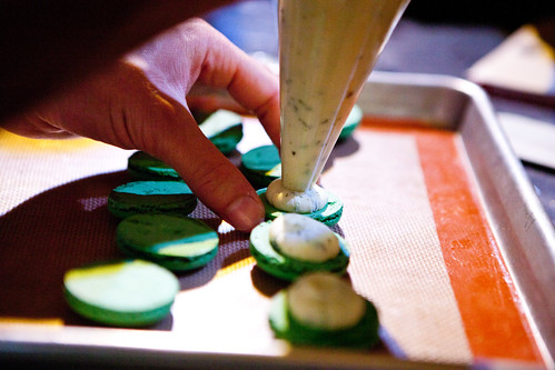 Piping out the mint ganache filling onto the macarons