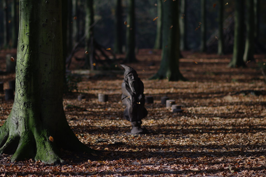 wooden gnome sculpture in falling leaves, Haagse Bos
