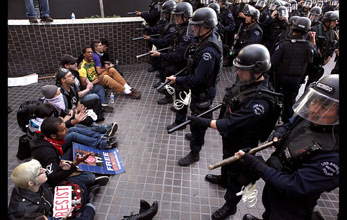 Occupy L.A. protesters sit with locked arms in front of a wave of approaching riot police during a protest in front of the Bank of America on Hope Street and 3rd Street. (Arkasha Stevenson/Los Angeles Times) by Pan-African News Wire File Photos