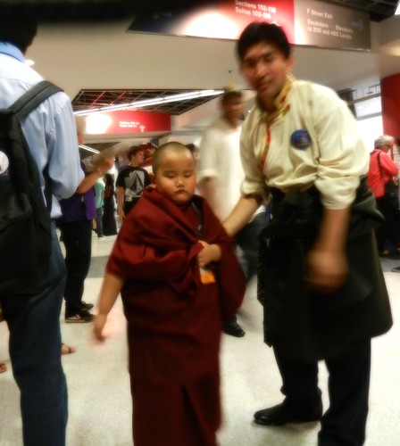 Young Taksham Tulku, & Sonam Sangpo, of Ugyen Mindroling Monastery, Clement Town, India, pauses to be photographed with a bright red ball of light energy apparently in his right hand, conclusion of Kalachakra for World Peace, Verizon Center, Washington DC by Wonderlane