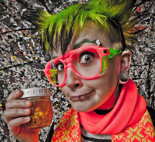 Girl with glasses and green hair holds jar of mysterious yellow liquid
