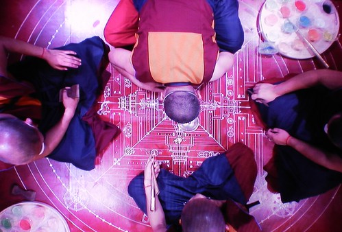 Tibetan Buddhist artist monks having created the blueprint now begin filling in the Kalachakra colored sand mandala while praying, and while other vow holders pray, from the monitor, Kalachakra for World Peace, Washington D.C., USA by Wonderlane
