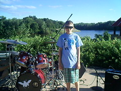 Michael Johnson, brother-in-law to Junebug drummer Tony L. Kollman and occasional drum roadie, poses next to Kollman's drumkit in the performance area at River's Edge Commons for Elk River, Minnesota's Chalk It Up event on July 12, 2011.