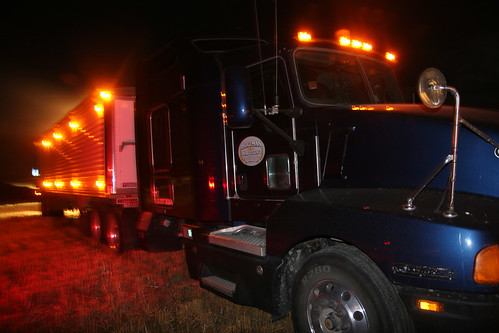 A truck parked with its lights on so the grain cart can easily find it in the field at night