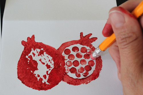 overhead picture of applying painted pencil eraser stamp to paper to make pomegranate on Rosh Hashanah card 
