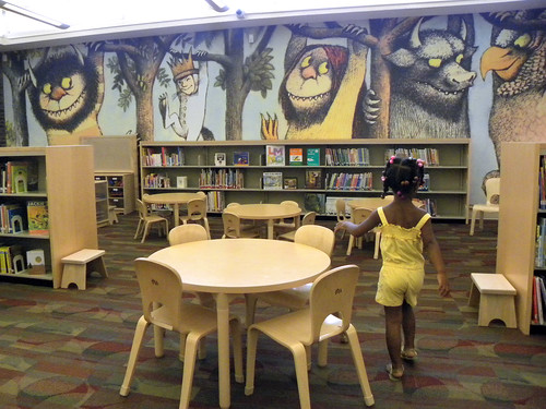 a little girl checks out the Wild Things wall by Enoch Pratt Free Library