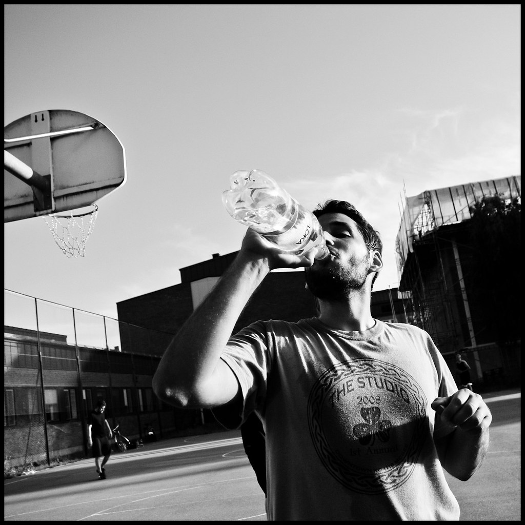 Man drinking water at basketball court, Uppsala, Sweden