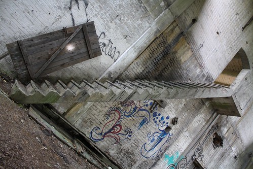 A tall slender staircase with no railings rises above the mural.