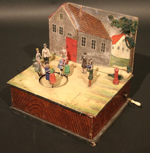 A 19th century Continental mechanical toy as a group of figures dancing before a house, which achieved £560