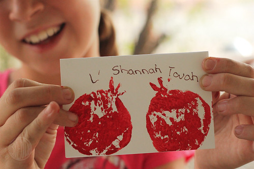 Girl holding a handmade L' Shana Tovah! card with a picture of pomegranate 