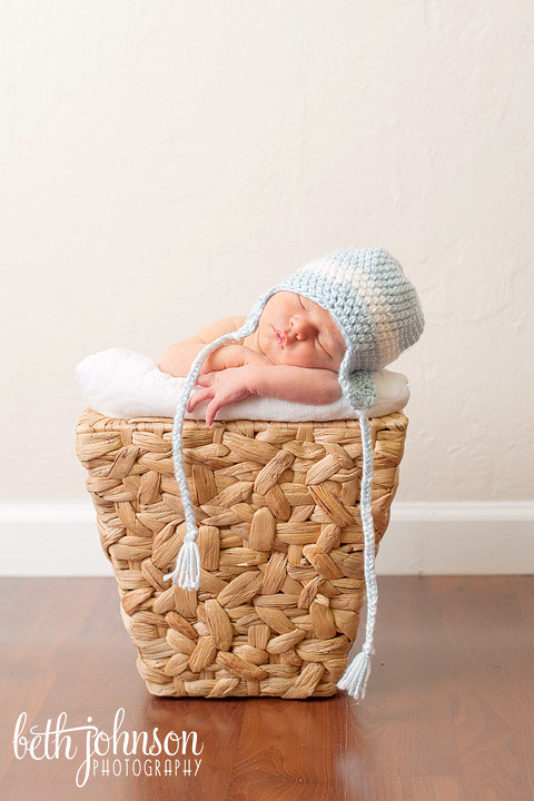 baby boy in blue and white hat in little basket