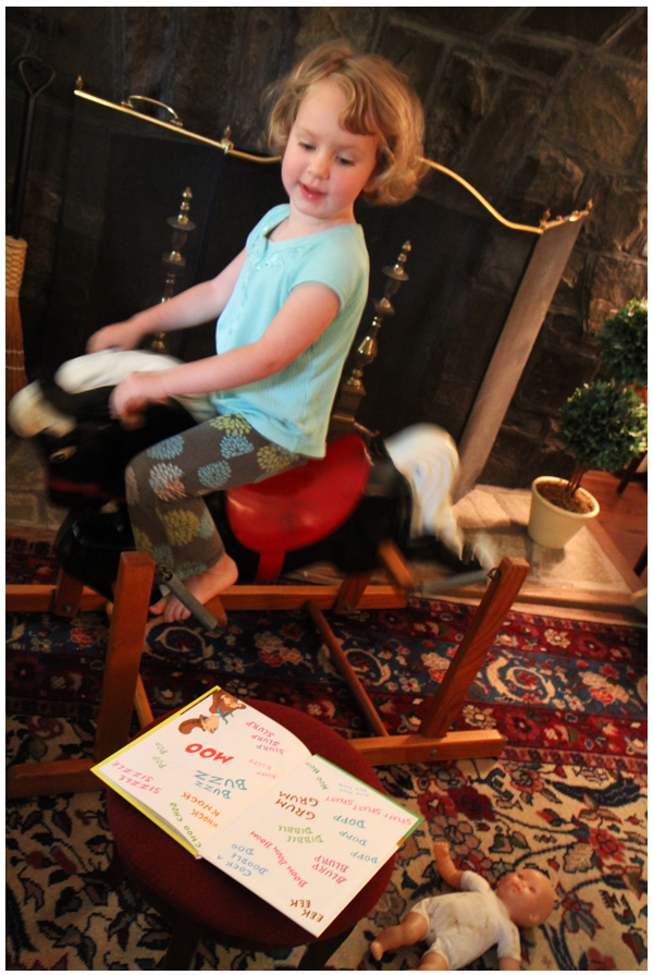 Reading activities: toddler reading while riding on a play horse