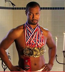Isaiah Mustafa, the Old Spice guy, wearing a dozen Olympic medals.