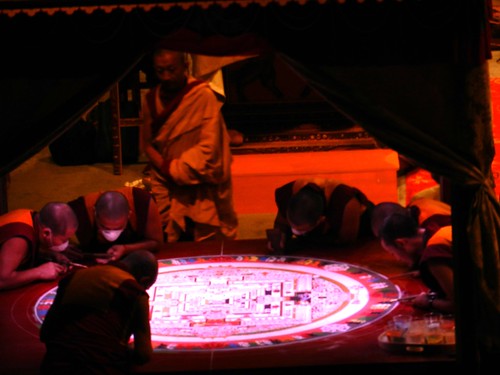 Artist monks working on completing the sand Kalachakra mandala inside the pavilion, stage, Kalachakra for World Peace, red light during a lighting change, Verizon Center, Washington D.C., USA by Wonderlane