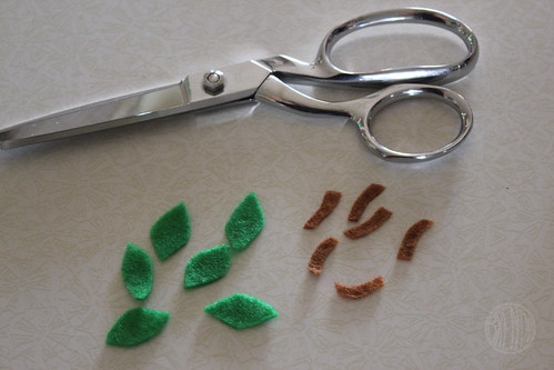 a pair of scissors with green and brown felt pieces 