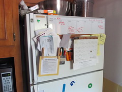 The freezer door with calendars and organizers on it.
