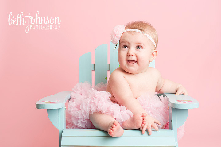 six month old baby girl in beach chair pink background