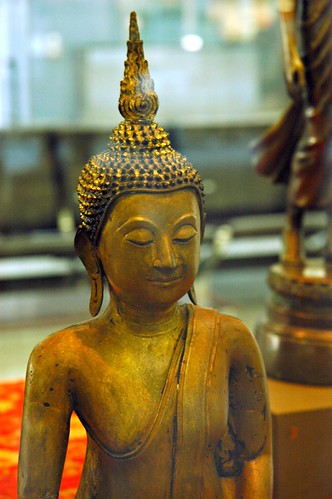 Eyes lowered - Burmese, Cambodian, or Thai statue of Lord Buddha, with the gold flame of wisdom on his head (and ushnisha), monk's robe, exhibit, San Francisco International Airport, San Francisco, California, USA by Wonderlane