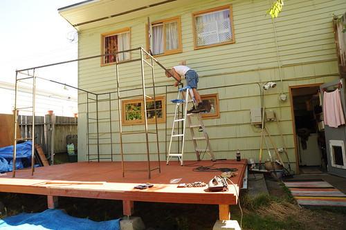 Mike constructing the wire frame for a gazebo, standing on a ladder, above the fresh deck, backyard, back door, carpet, windows, Broadview, Seattle, Washington, USA by Wonderlane