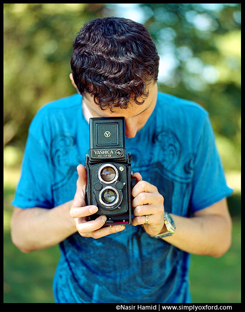 A photographer holding a Yashica twin lens reflex camera