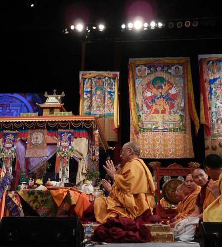 Transition during prayers: Tibetan Buddhist Khenpo leading lamas in offerings to the deities, facing the Kalachakra pavilon, Thankgas of Padmasambhava, Kalachakra, Buddha, Kalachakra Mandala, Verizon Center, Washington D.C., USA by Wonderlane
