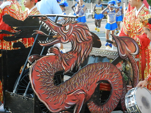 Chinese Dragon Drum bike, traditional red costumes, blue dancers in background, snare drum,  Greenwood Parade, Seattle, Washington, USA by Wonderlane