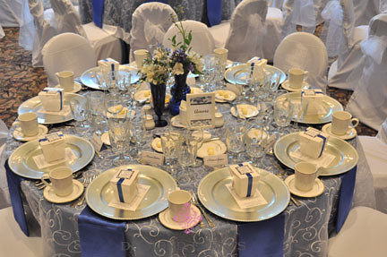 Table setting for a wedding white embroidered overlay and blue satin 