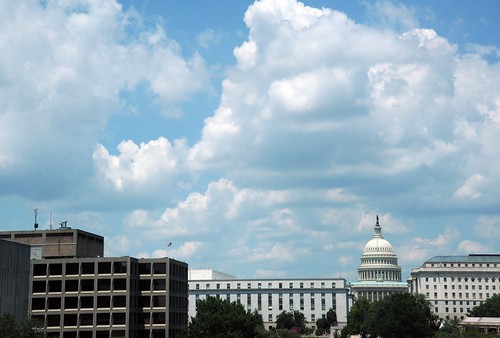 The US Capitol Building seen between federal buildings, under mounds of clouds on a hot summer day, Washington D.C., USA by Wonderlane