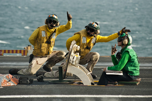 Sailors signal the launch of an F/A-18F Super Hornet.